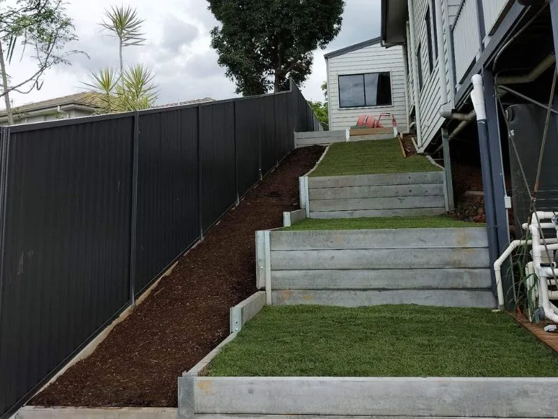 After concrete sleeper retaining walls and fencing on sloped property